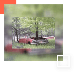 A red car is parked in the grass.